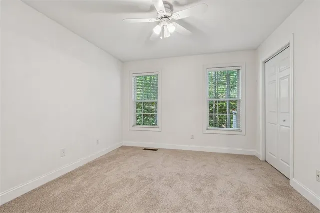 an empty room with a ceiling fan and windows