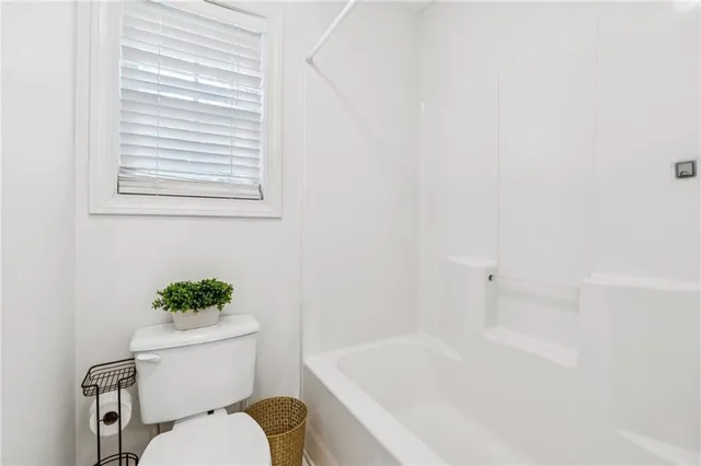 a white toilet sitting next to a bath tub