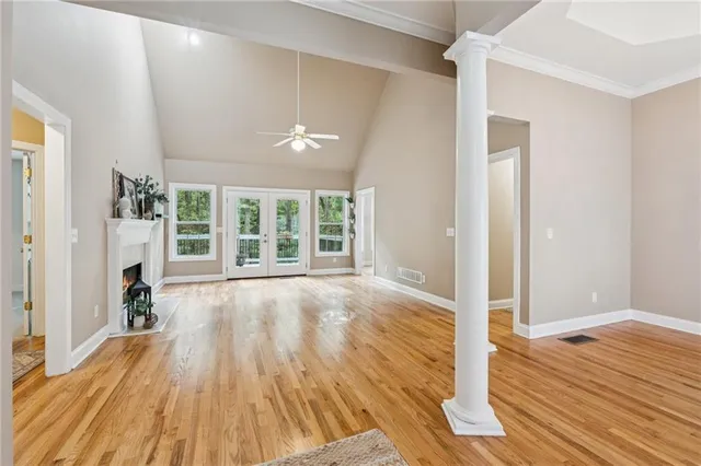 a view of an empty room with wooden floor and a window