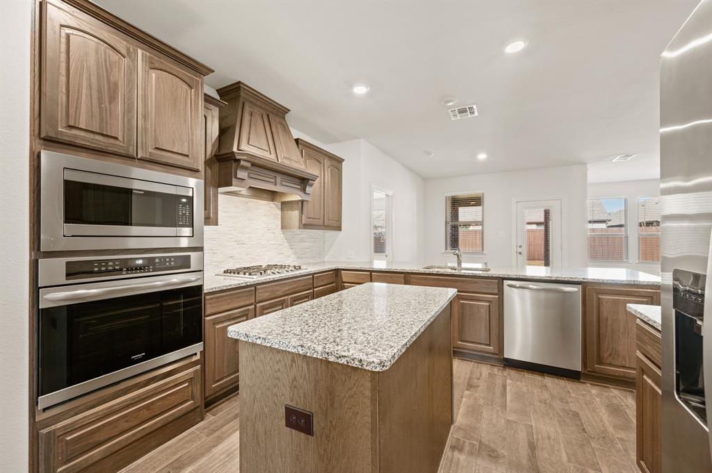 10920 Calvert Place McKinney, TX 75071 - Photo 12 of 37 a kitchen with stainless steel appliances granite countertop a kitchen island a stove a sink a microwave and cabinets