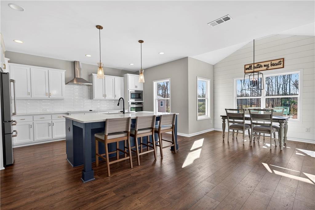 103 Hammond Road Griffin, GA 30223 - Photo 45 of 76 a open kitchen with stainless steel appliances granite countertop a stove a refrigerator a kitchen island a dining table and chairs with wooden floor