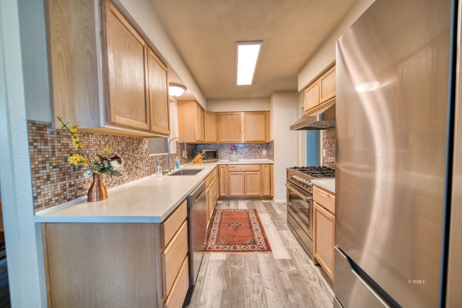 4047 Felspar Avenue Ridgecrest, CA 93555 - Photo 7 of 49 a kitchen with stainless steel appliances granite countertop a refrigerator a sink dishwasher a stove and white countertops with wooden floor