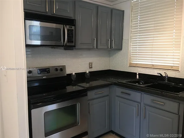 a kitchen with granite countertop cabinets sink and stainless steel appliances