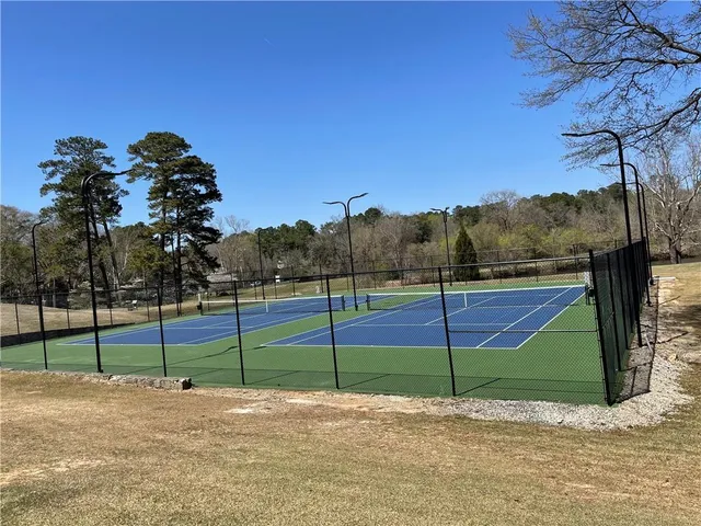 a view of a tennis ground with large trees