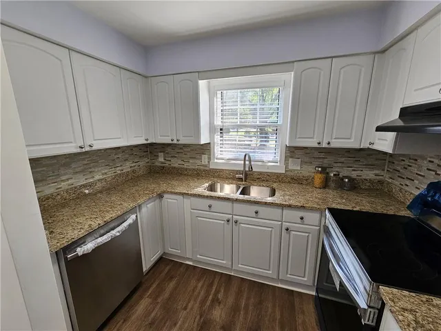a kitchen with granite countertop sink stove and cabinets