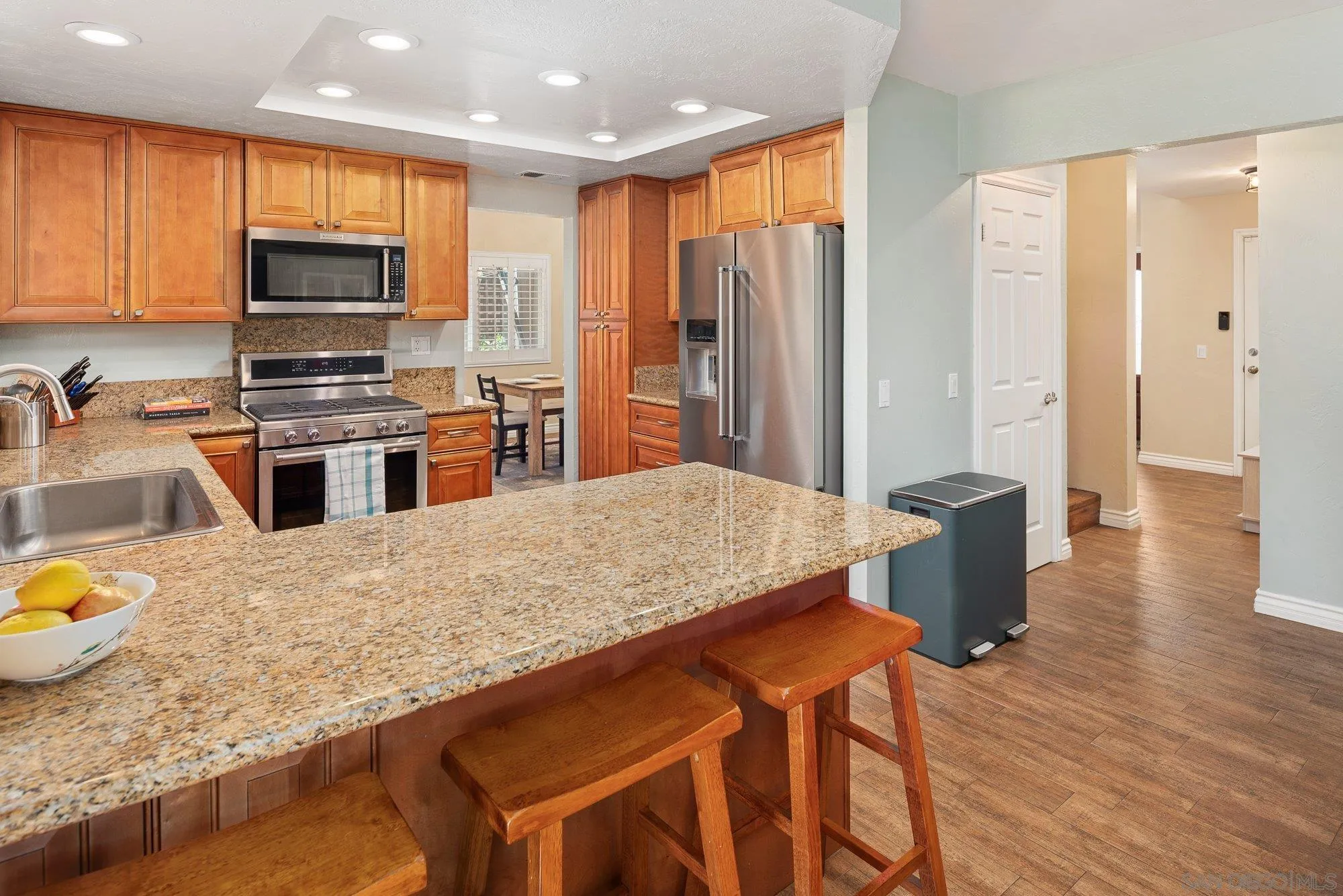 10246 Princess Joann Road Santee, CA 92071 - Photo 13 of 48 a kitchen with stainless steel appliances granite countertop a stove top oven a sink dishwasher a dining table and chairs with wooden floor