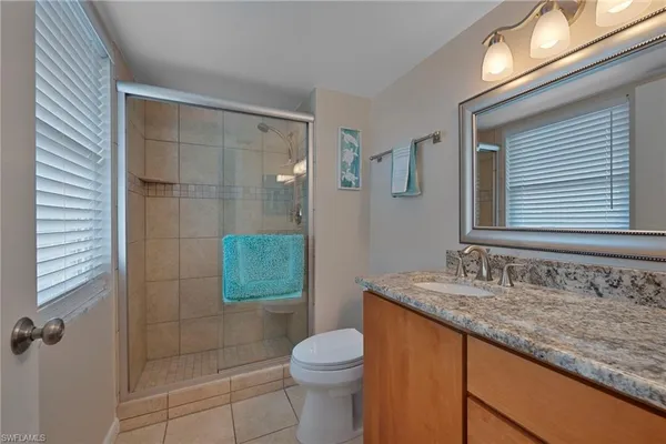 a bathroom with a granite countertop sink a mirror and a toilet
