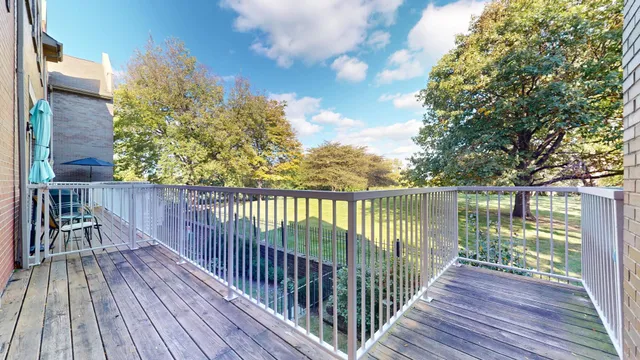 a balcony with wooden floor next to a yard