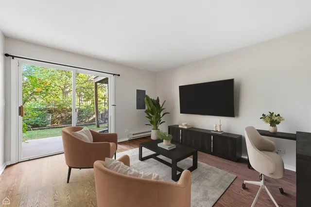 a living room with furniture floor to ceiling window hardwood floor and a flat screen tv