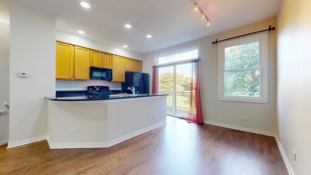 a view of kitchen with stainless steel appliances granite countertop a stove a sink a refrigerator with wooden floor and cabinets