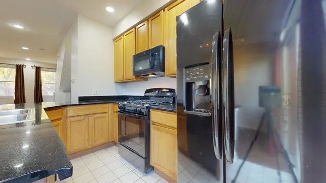 a kitchen with stainless steel appliances granite countertop a refrigerator a stove and a sink
