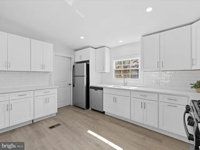 a large white kitchen with cabinets and wooden floor