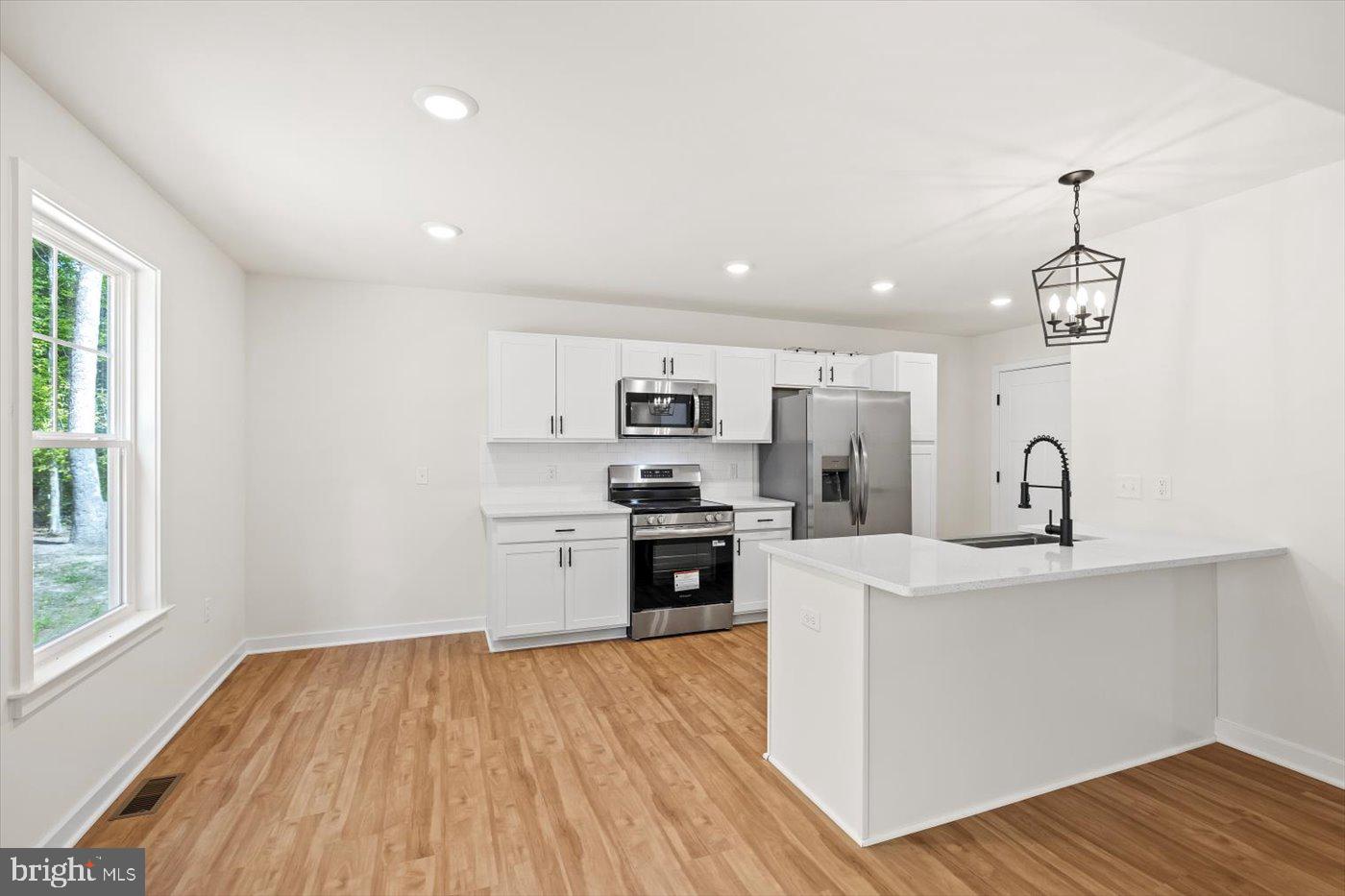 736 Circle Lane Colonial Beach, VA 22443 - Photo 16 of 40 a kitchen with stainless steel appliances a stove top oven a sink dishwasher and a refrigerator with wooden floor