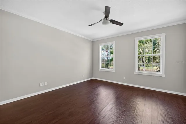 a view of empty room with wooden floor and fan