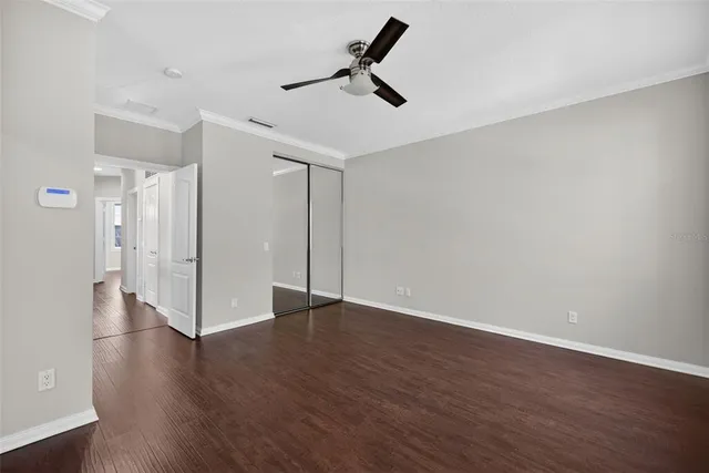 an empty room with wooden floor ceiling fan and window