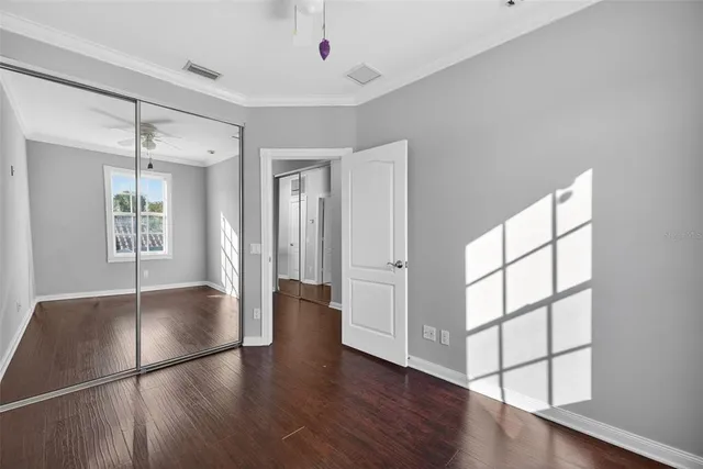 an empty room with wooden floor and windows with curtains