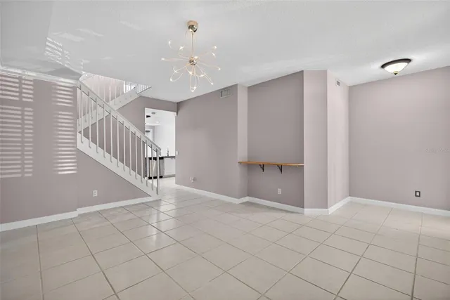 a view of an empty room with stairs and a chandelier fan