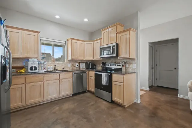 a kitchen with stainless steel appliances granite countertop a refrigerator and a stove top oven