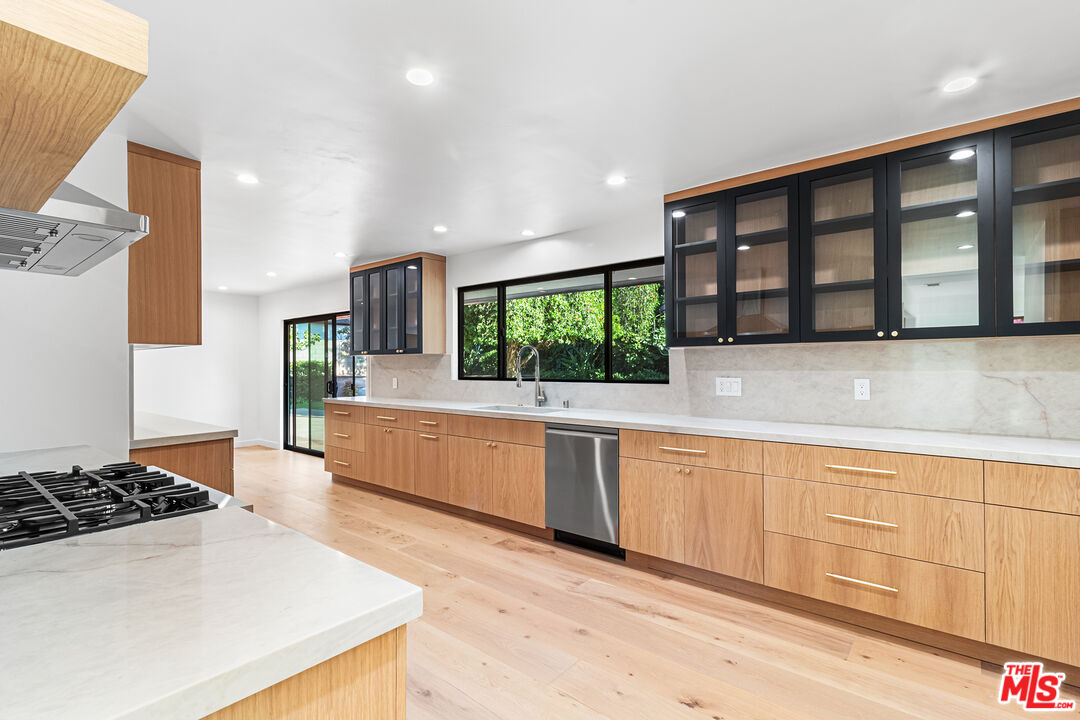 a large kitchen with stainless steel appliances granite countertop a large window and a counter space