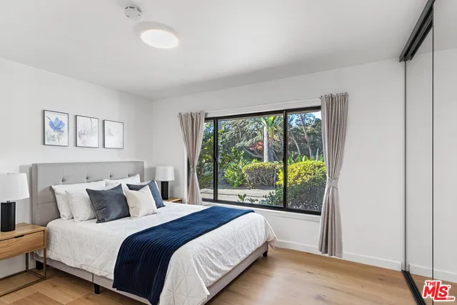 a bedroom with a balcony a bed and a large window