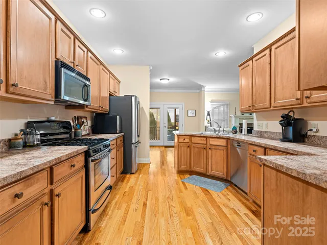 a open kitchen with stainless steel appliances granite countertop a stove a sink dishwasher and a refrigerator with wooden floor