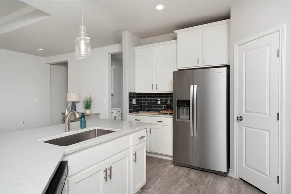 a kitchen with a refrigerator a sink and white cabinets