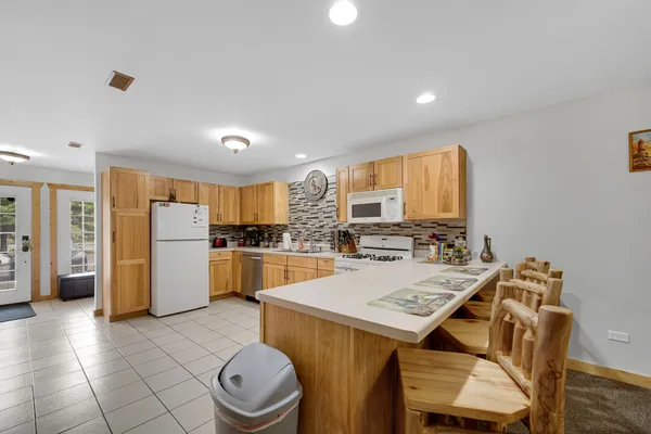 a kitchen with a refrigerator a stove top oven a sink a dining table and chairs