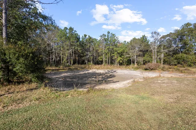 a view of dirt field with trees in the background