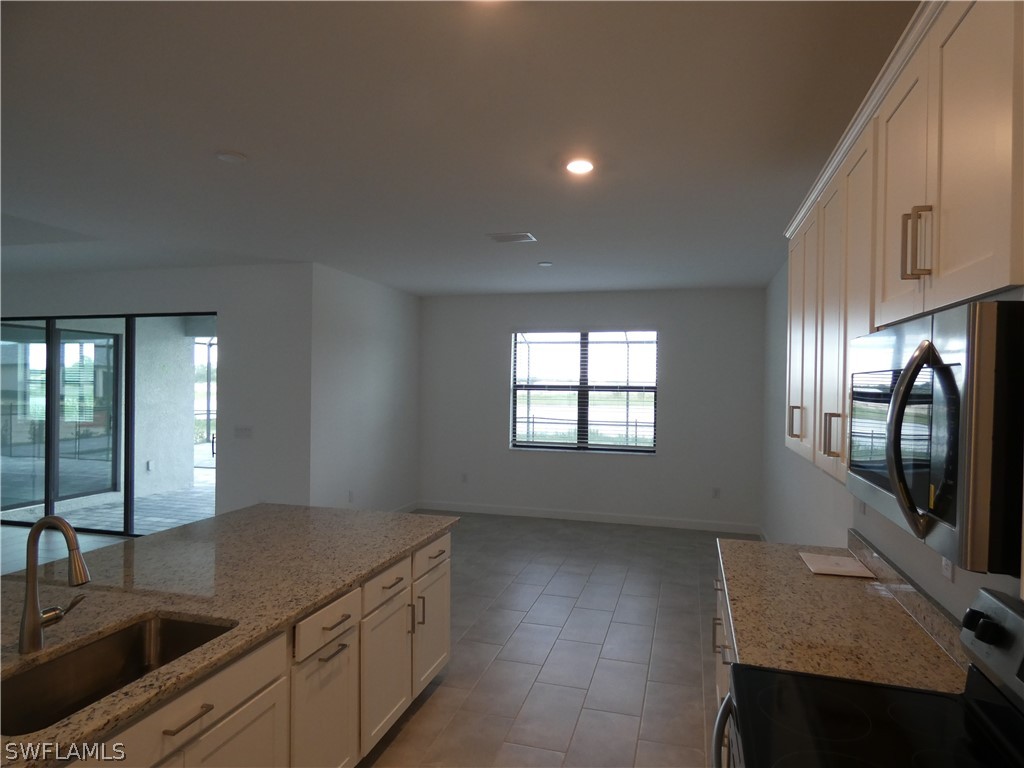 11379 Canopy Loop Fort Myers, FL 33913 - Photo 3 of 24 a kitchen with stainless steel appliances granite countertop a sink a stove and a refrigerator