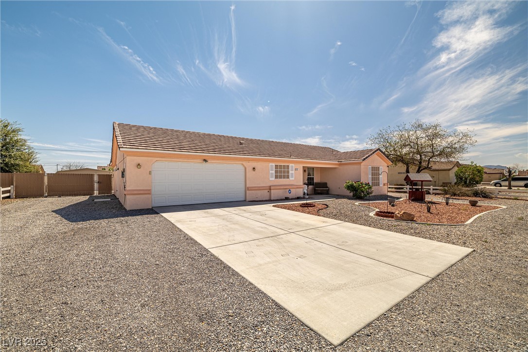 81 Diamond Bar Road Pahrump, NV 89048 - Photo 3 of 38 Ranch-style home with concrete driveway, stucco siding, a garage, a tiled roof, and fence