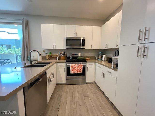 11238 Essence Point Avenue, Unit 210 Las Vegas, NV 89135 - Photo 5 of 28 Kitchen with stainless steel appliances, white cabinetry, light wood-style flooring, a peninsula, and light stone countertops