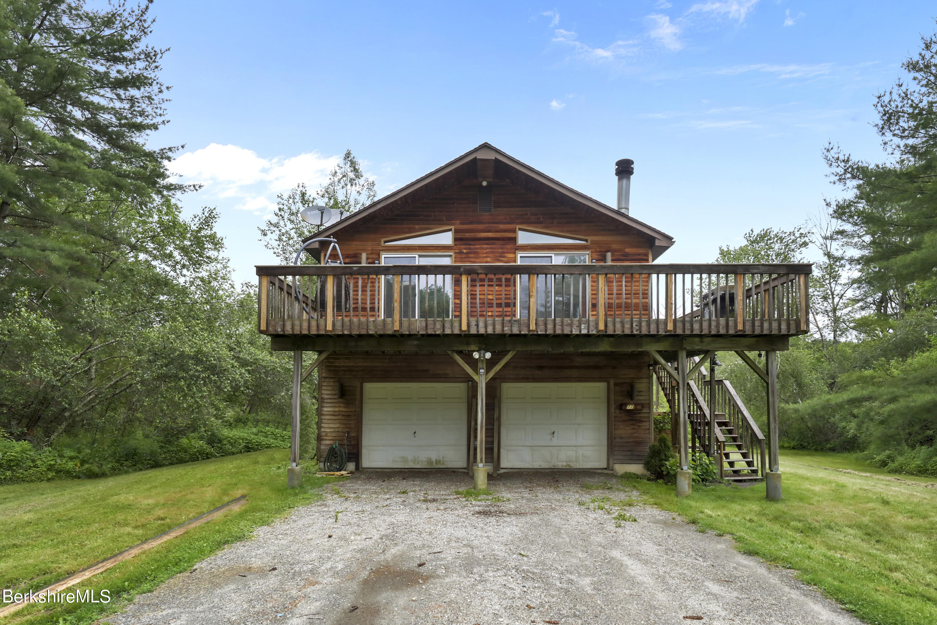 77 Shawnee Shore Road Becket, MA 01223 - Photo 1 of 28 a view of a wooden house with a big yard and large trees