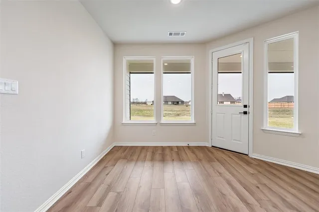 a view of an empty room with wooden floor and a fireplace