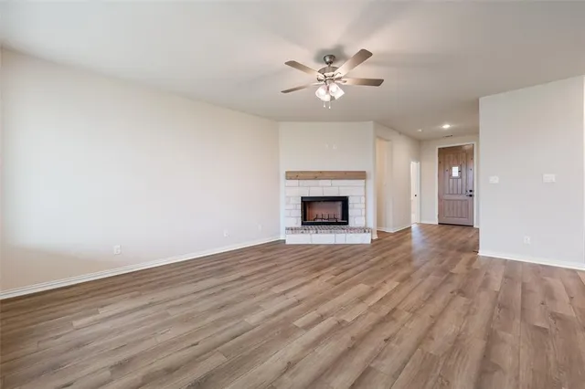 a view of empty room with wooden floor and fireplace