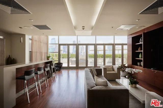 a living room with furniture large windows and wooden floor