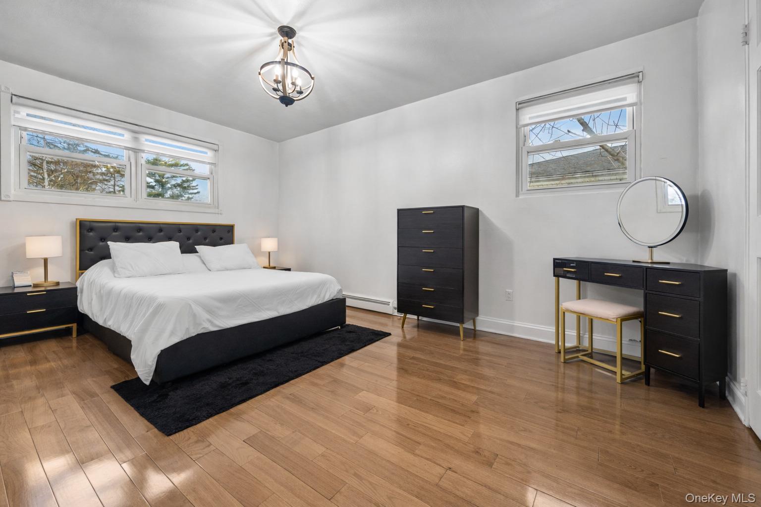 1016 Westwood Road Woodmere, NY 11598 - Photo 8 of 23 Bedroom featuring wood finished floors, a baseboard heating unit, and a chandelier