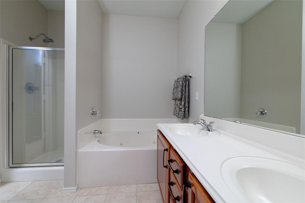 4025 Chisos Rim Trail Fort Worth, TX 76244 - Photo 24 of 40 Bathroom featuring a dual vanity with a wood-finish cabinet, large wall-mounted mirror, soaking tub with jets, and a glass-enclosed shower