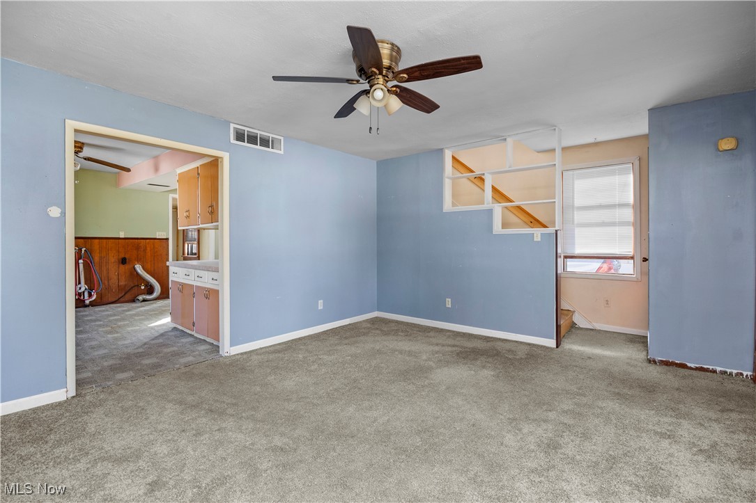 6927 North Wildacre Road Curtice, OH 43412 - Photo 12 of 44 Carpeted empty room featuring ceiling fan, wood walls, and wainscoting