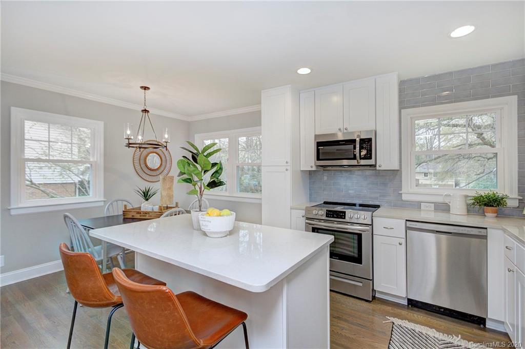 3908 Farmview Road Charlotte, NC 28205 - Photo 11 of 25 a kitchen with a stove a sink a dining table and chairs