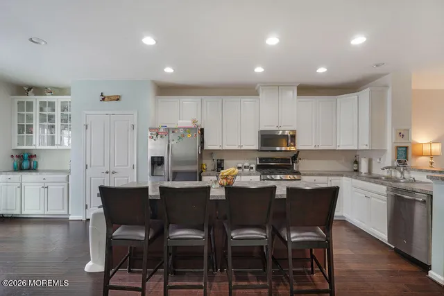 a kitchen with granite countertop a refrigerator a stove a dining table and chairs