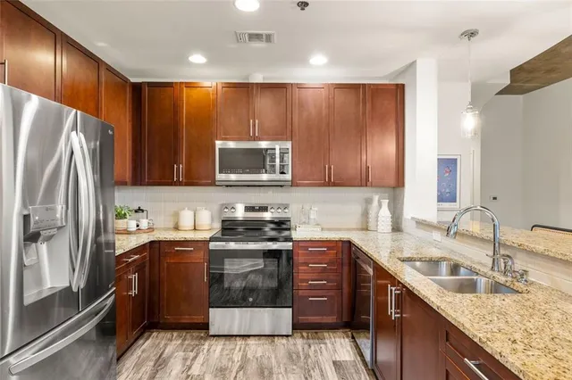 a kitchen with stainless steel appliances granite countertop a refrigerator stove a sink dishwasher and microwave oven