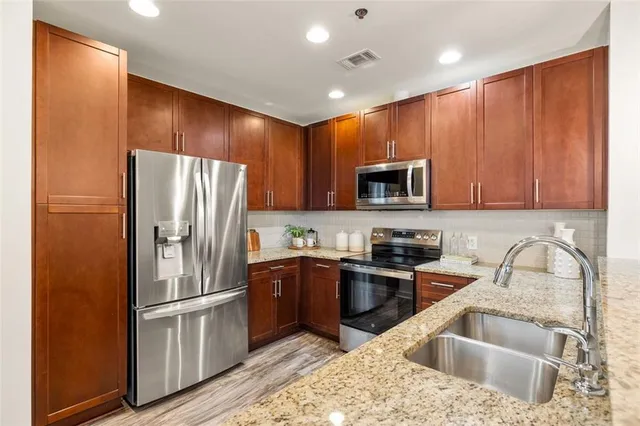 a kitchen with granite countertop stainless steel appliances a refrigerator a stove a sink cabinets and a counter top space