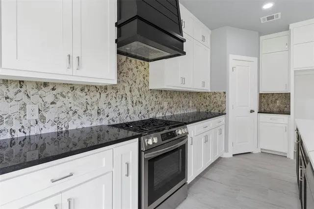 a kitchen with granite countertop white cabinets and stainless steel appliances