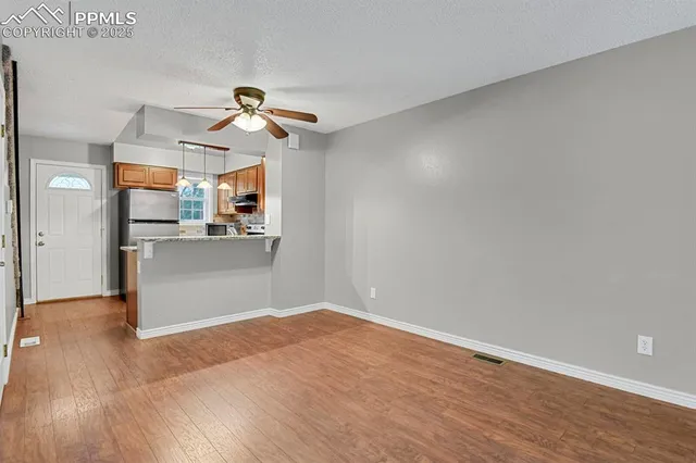 a view of a kitchen with wooden floor and a ceiling fan