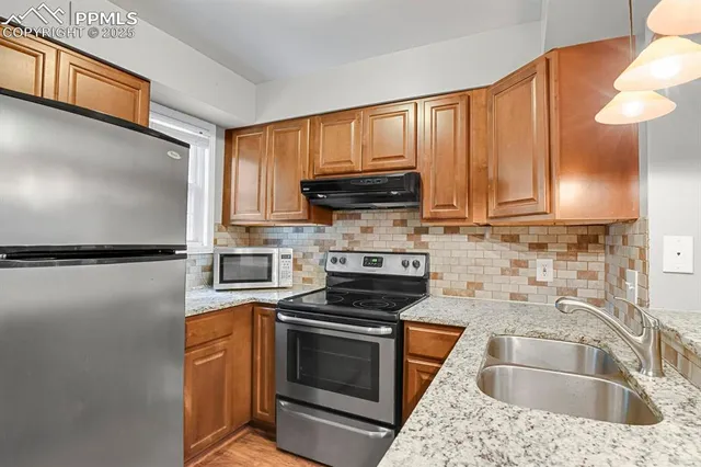 a kitchen with granite countertop a sink stove and microwave