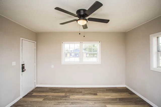 a view of an empty room with wooden floor and a window