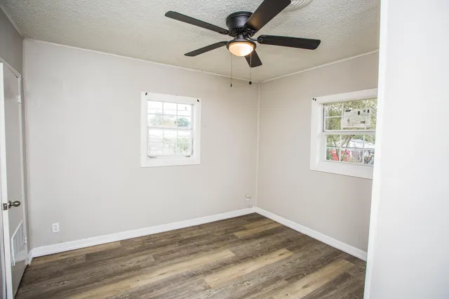 an empty room with wooden floor and ceiling fan