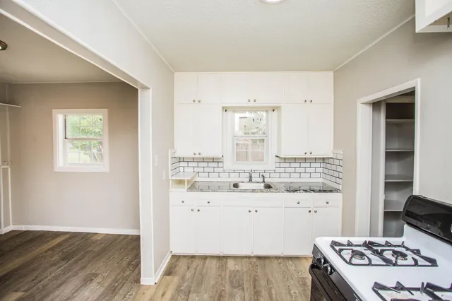 a kitchen with a stove and a wooden floor