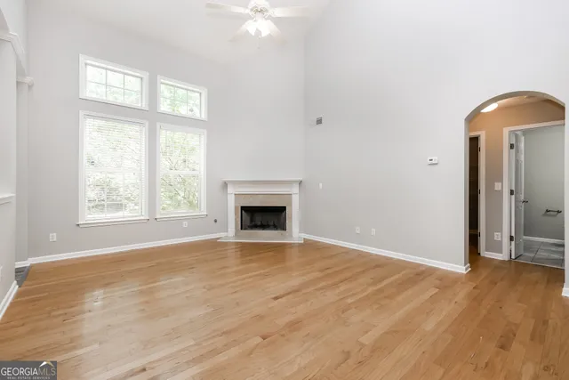 an empty room with windows fireplace and wooden floor