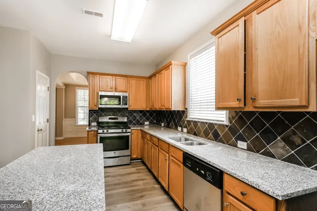 a kitchen with stainless steel appliances granite countertop a stove a sink and a microwave